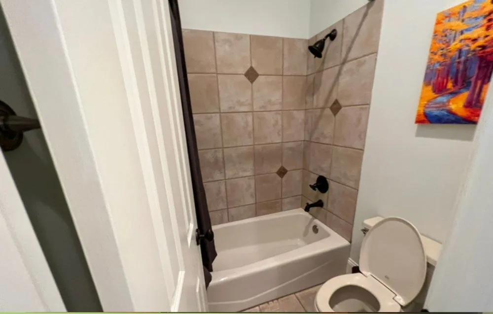 Bathroom before renovation, with beige tile and a builder tub