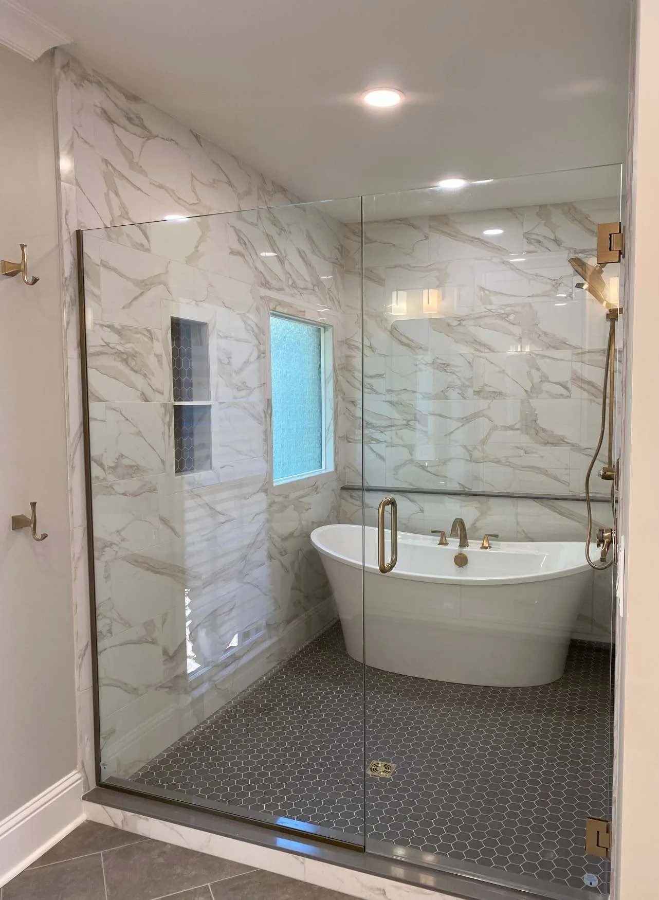 Bathroom remodel with a freestanding tub, marble walls and brass fixtures