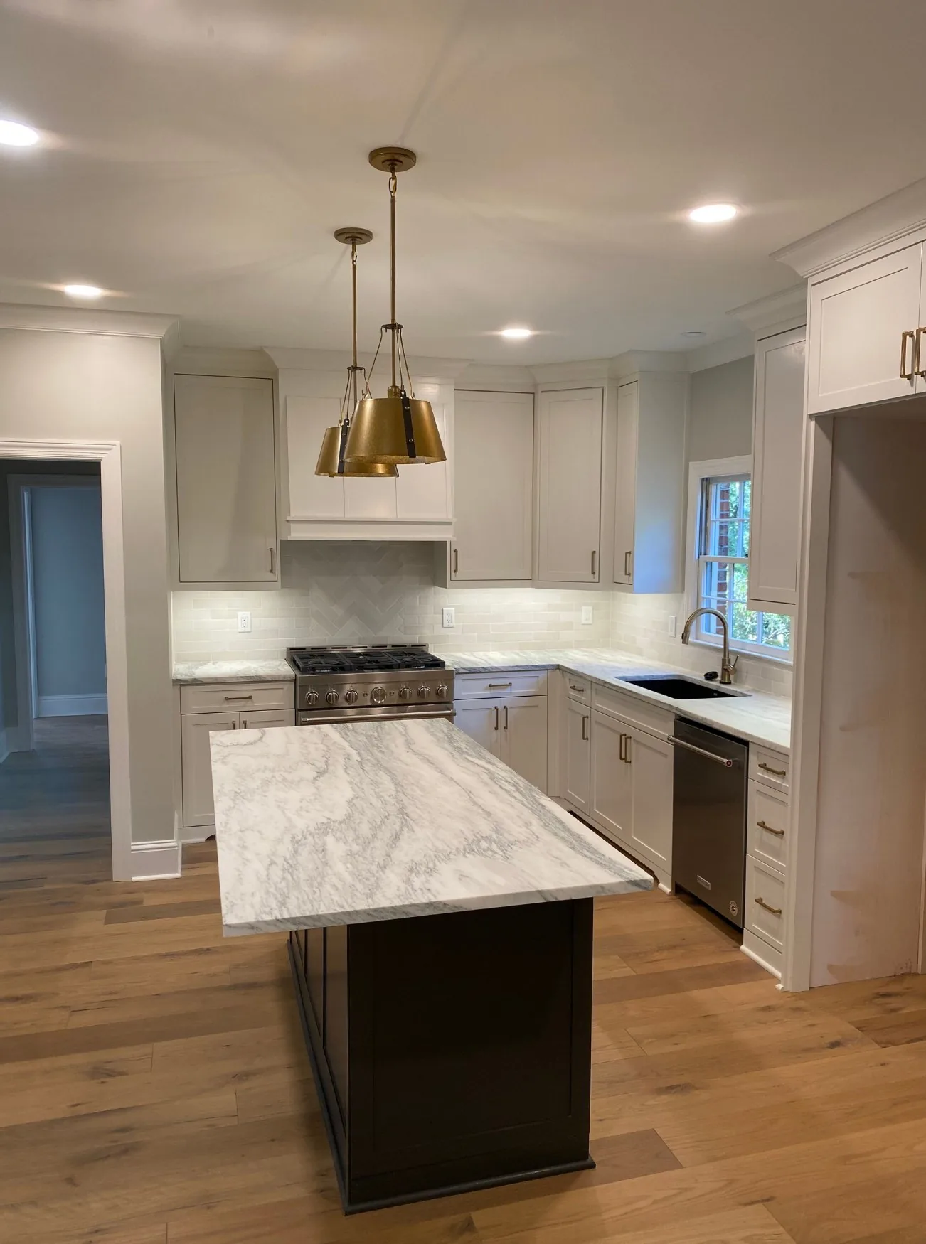 Remodeled kitchen with a marble island and brass pendant light