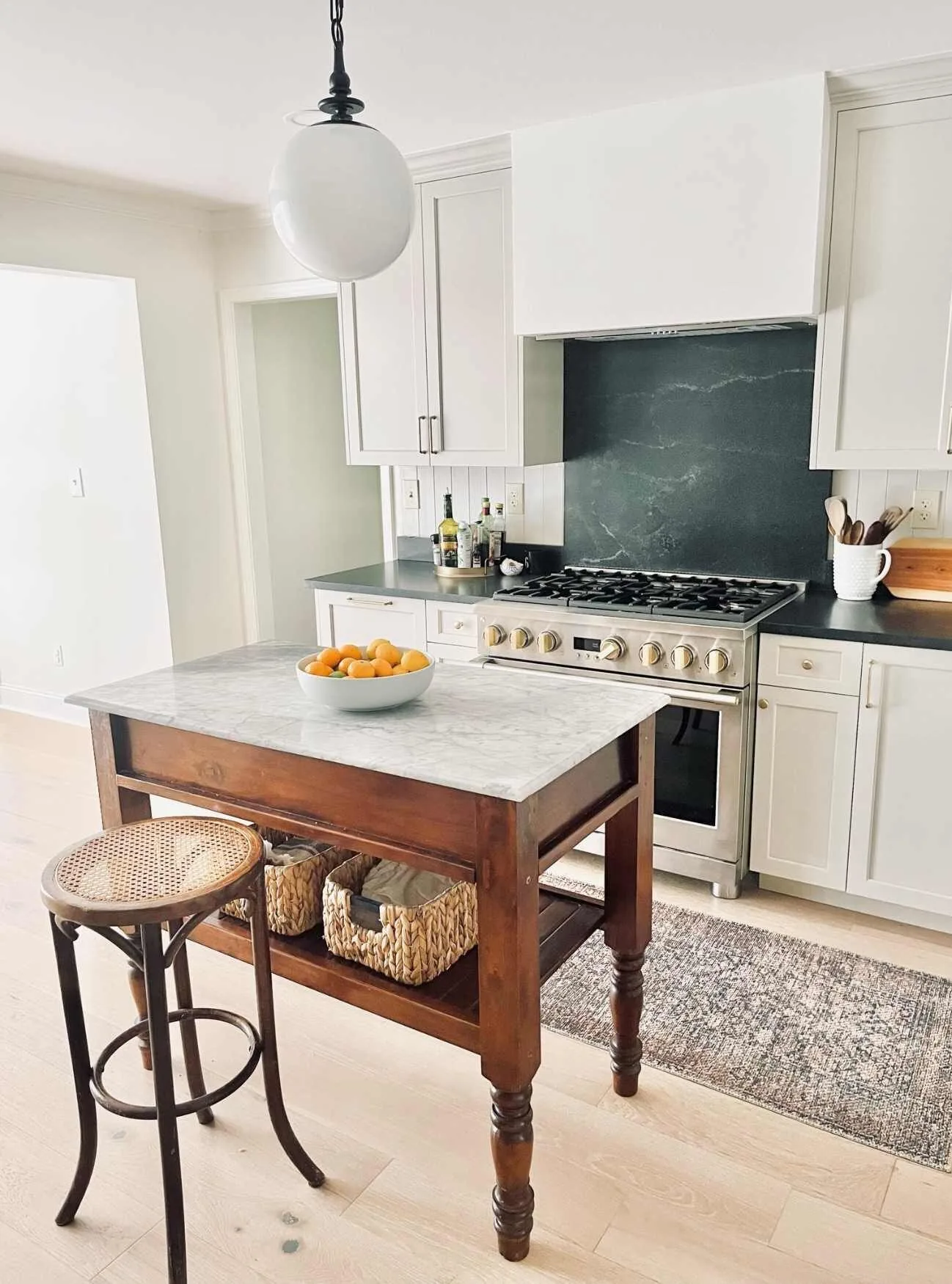 Kitchen remodel with a marble topped work island and a dark stone backsplash