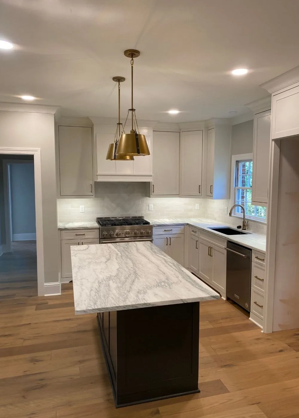 Kitchen with a dark stained island and brass pendant lights