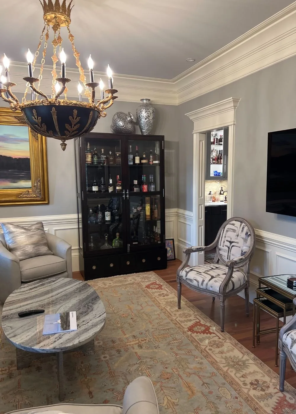 Living room with a chandelier, built in cabinet and wide trim