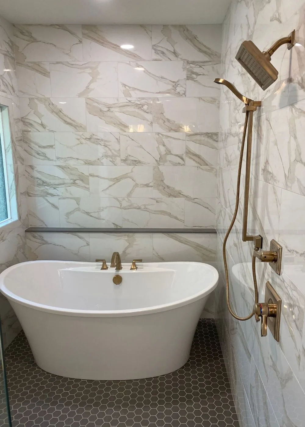 Marble shower surround with a freestanding tub and brass fittings